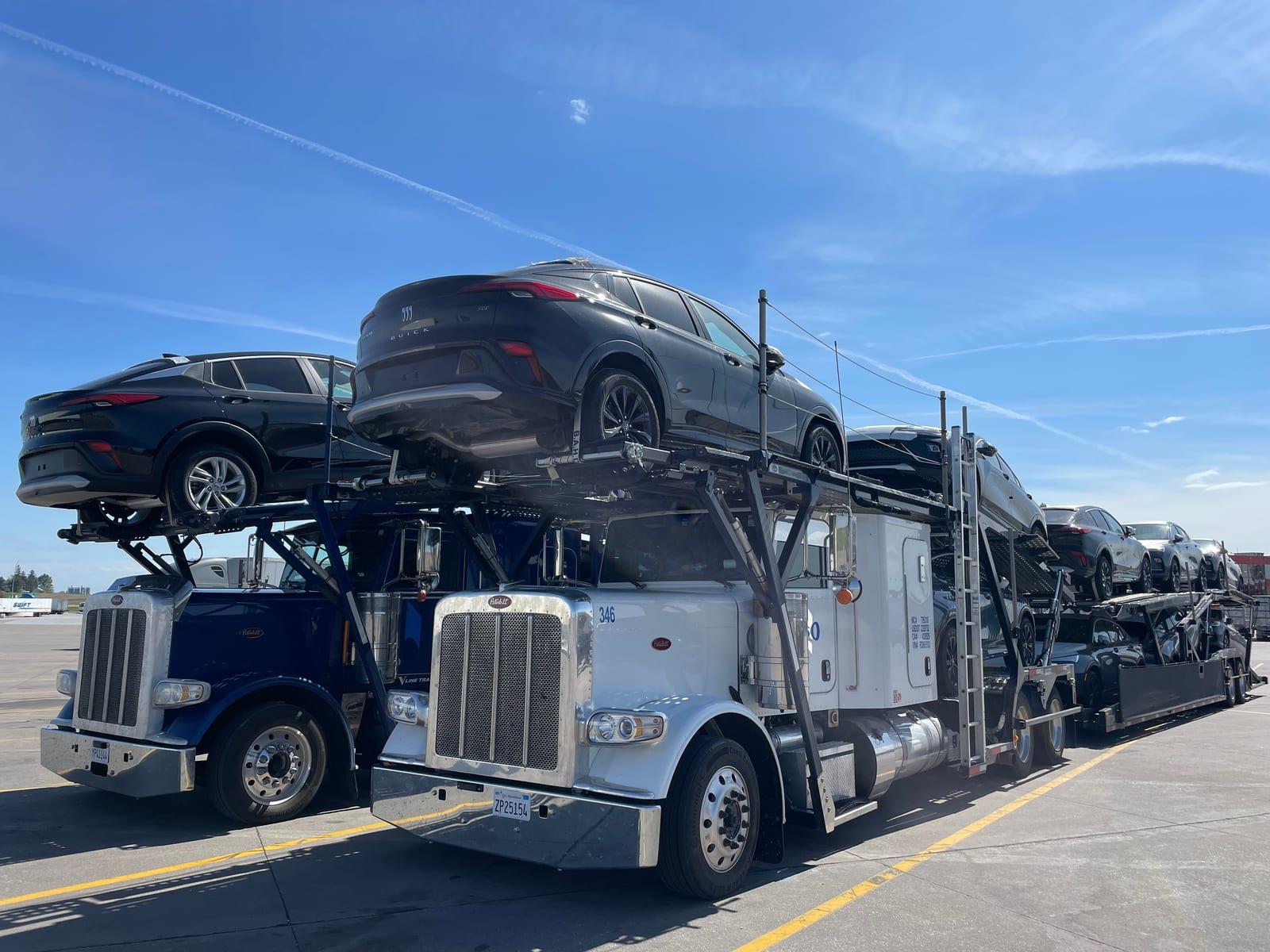 Two Osso car haulers loaded with new SUVs at a truck stop